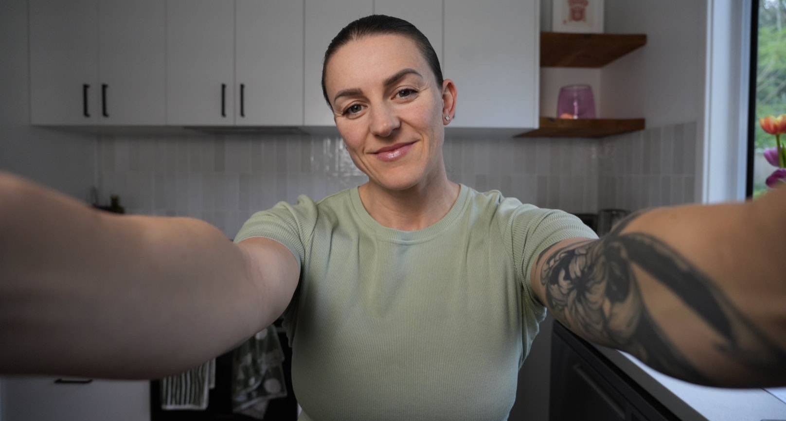 Kate, the nutrition coach behind Healthly, smiling in her kitchen.